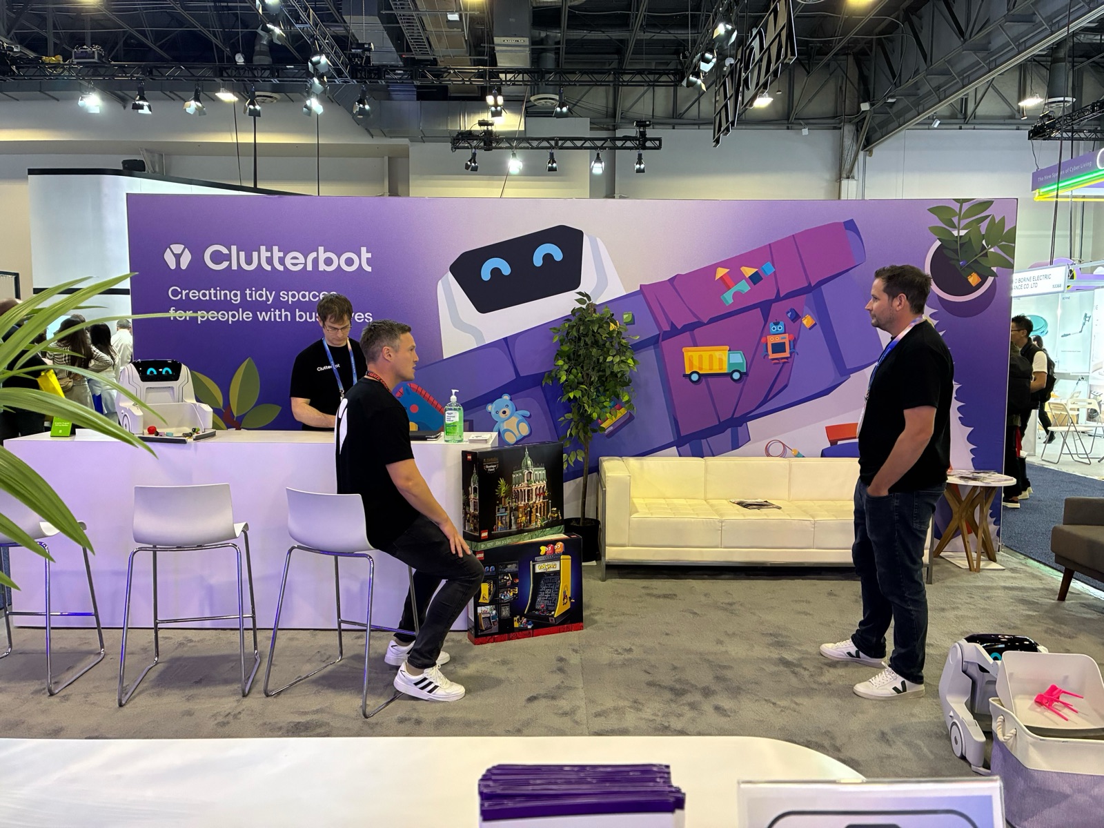 The Clutterbot team talking with visitors at the Clutterbot exhibition booth, with the robot on display