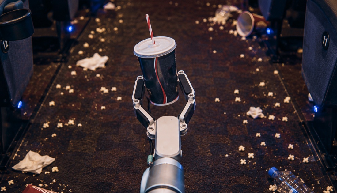 A robot arm picking up a cup between cinema seats