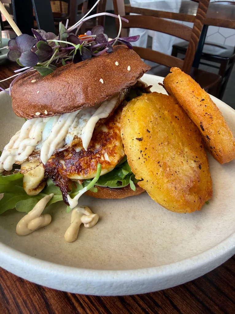 A halloumi burger with a fried egg, aioli, rocket and two golden hash browns.