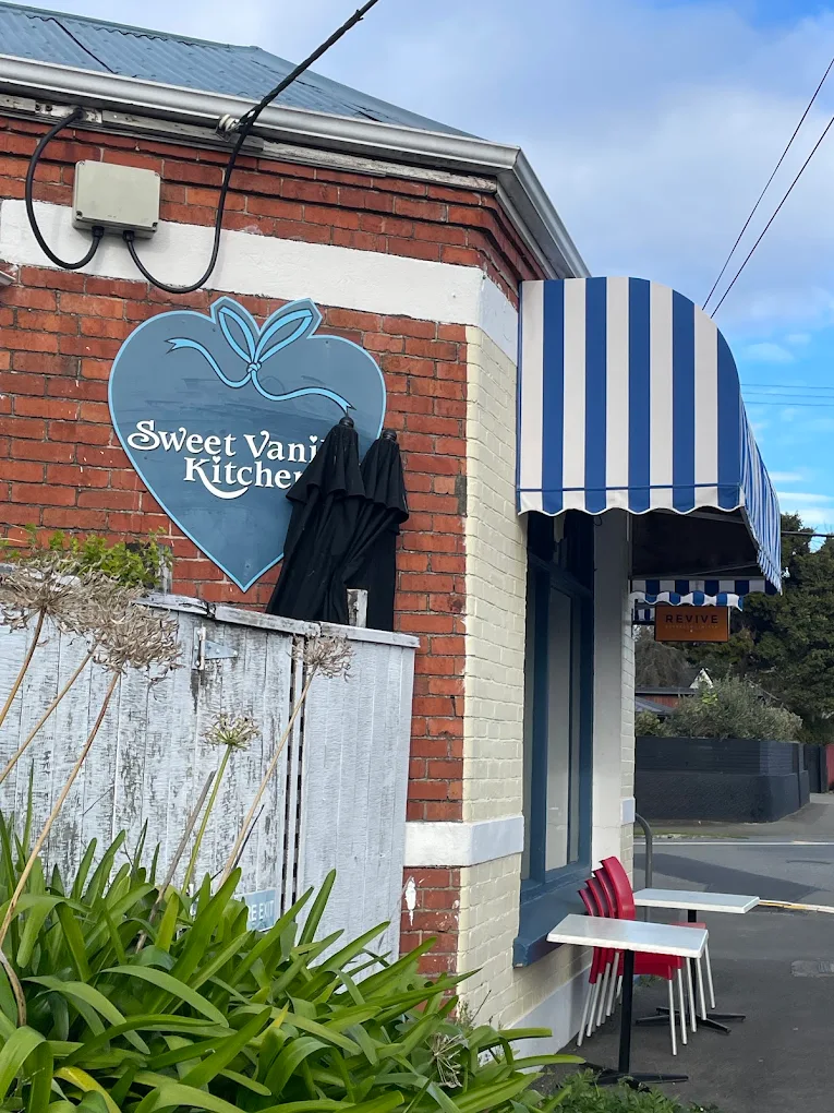 The blue heart-shaped Sweet Vanilla Kitchen sign on the café's red brick wall.