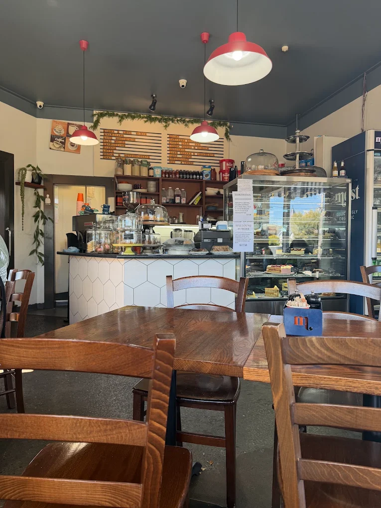 The counter with jars of cookies, cake domes and the coffee menu board on the wall.